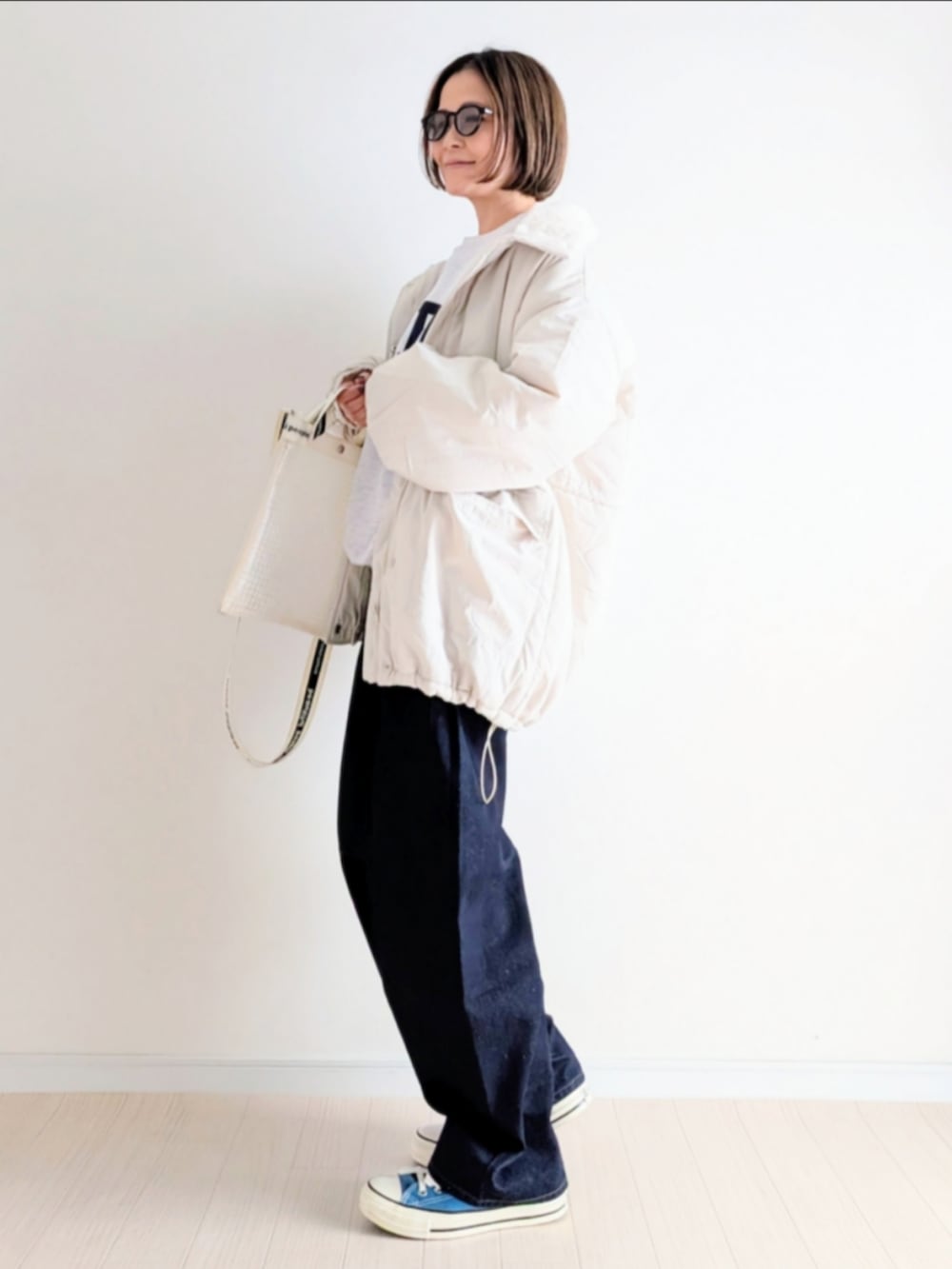 ホワイト系のブルゾン、ホワイト系のスウェット、ブルー系のデニムパンツを着用したレディースの冬コーディネートの3枚目の写真