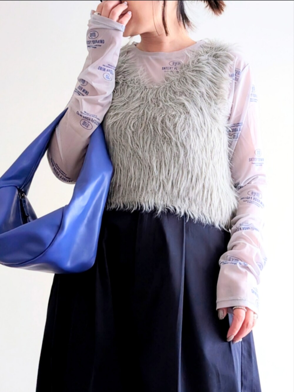 ベージュ系のベスト、ブルー系のチノパンツ、ブルー系のハンドバッグを着用したレディースの春コーディネートの5枚目の写真