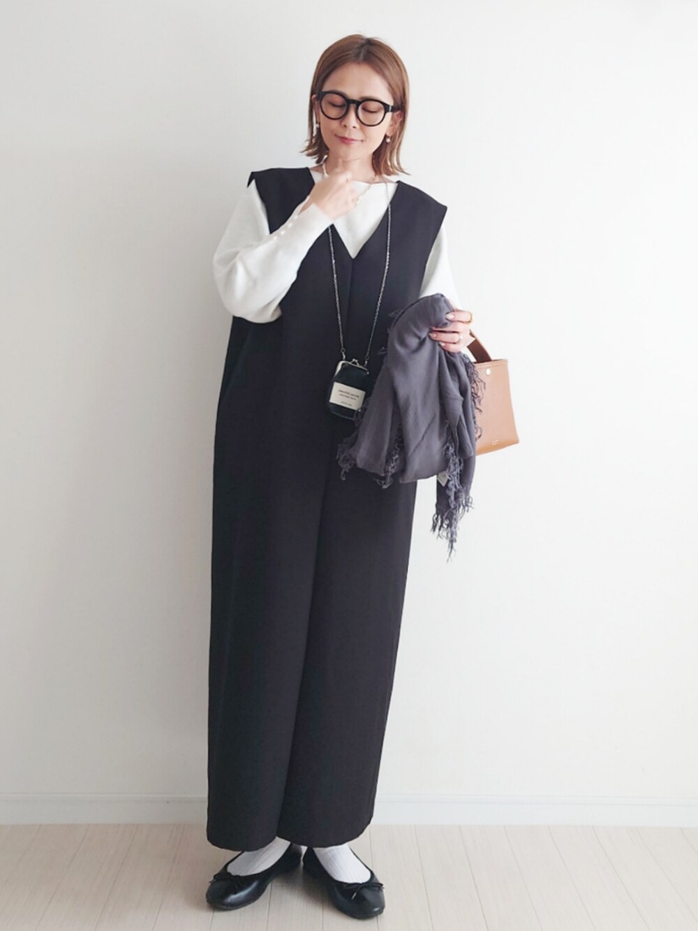 ブラック系のジャンパースカート、ホワイト系のニット/セーター、ブラック系のバレエシューズを着用したレディースの冬コーディネートの3枚目の写真