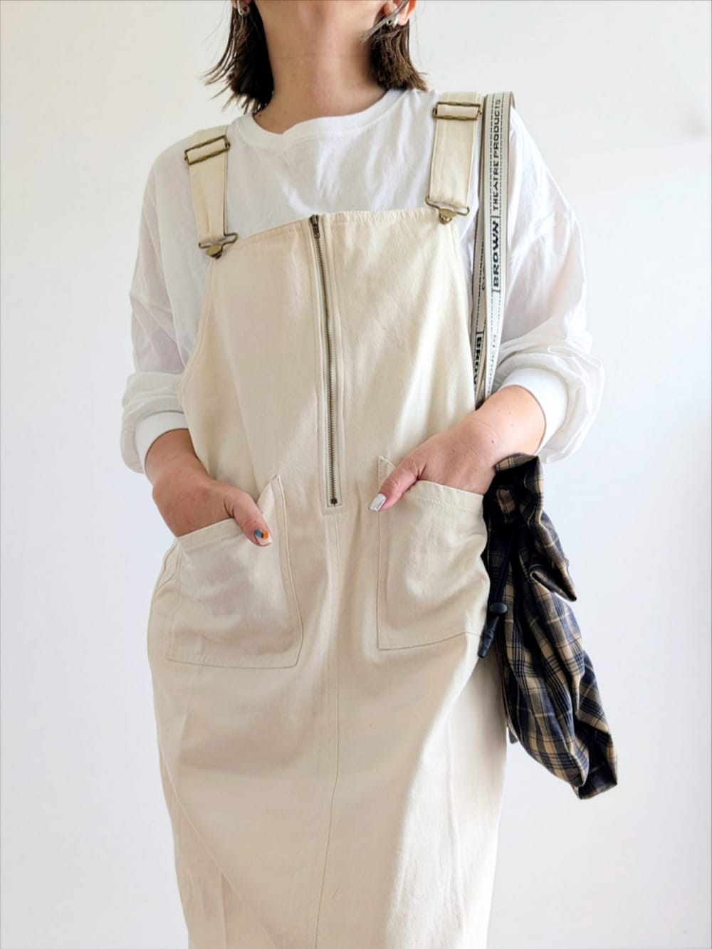 ホワイト系のジャンパースカート、ホワイト系のTシャツ/カットソー、ベージュ系のスニーカーを着用したレディースの秋コーディネートの4枚目の写真