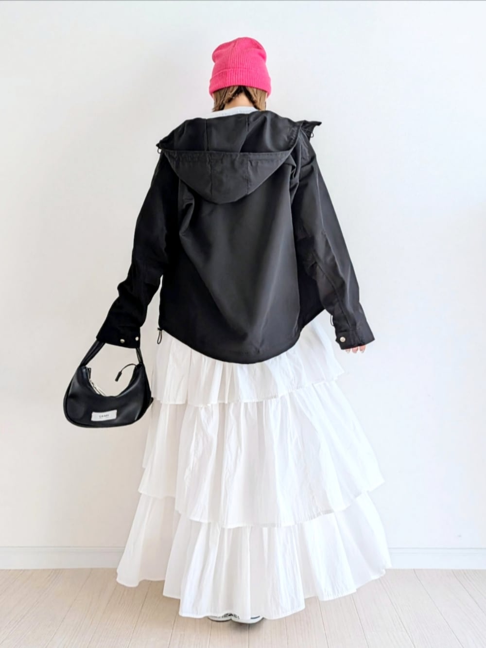 ホワイト系のスカート、ブラック系のハンドバッグ、ブラック系のマウンテンパーカーを着用したレディースの冬コーディネートの3枚目の写真