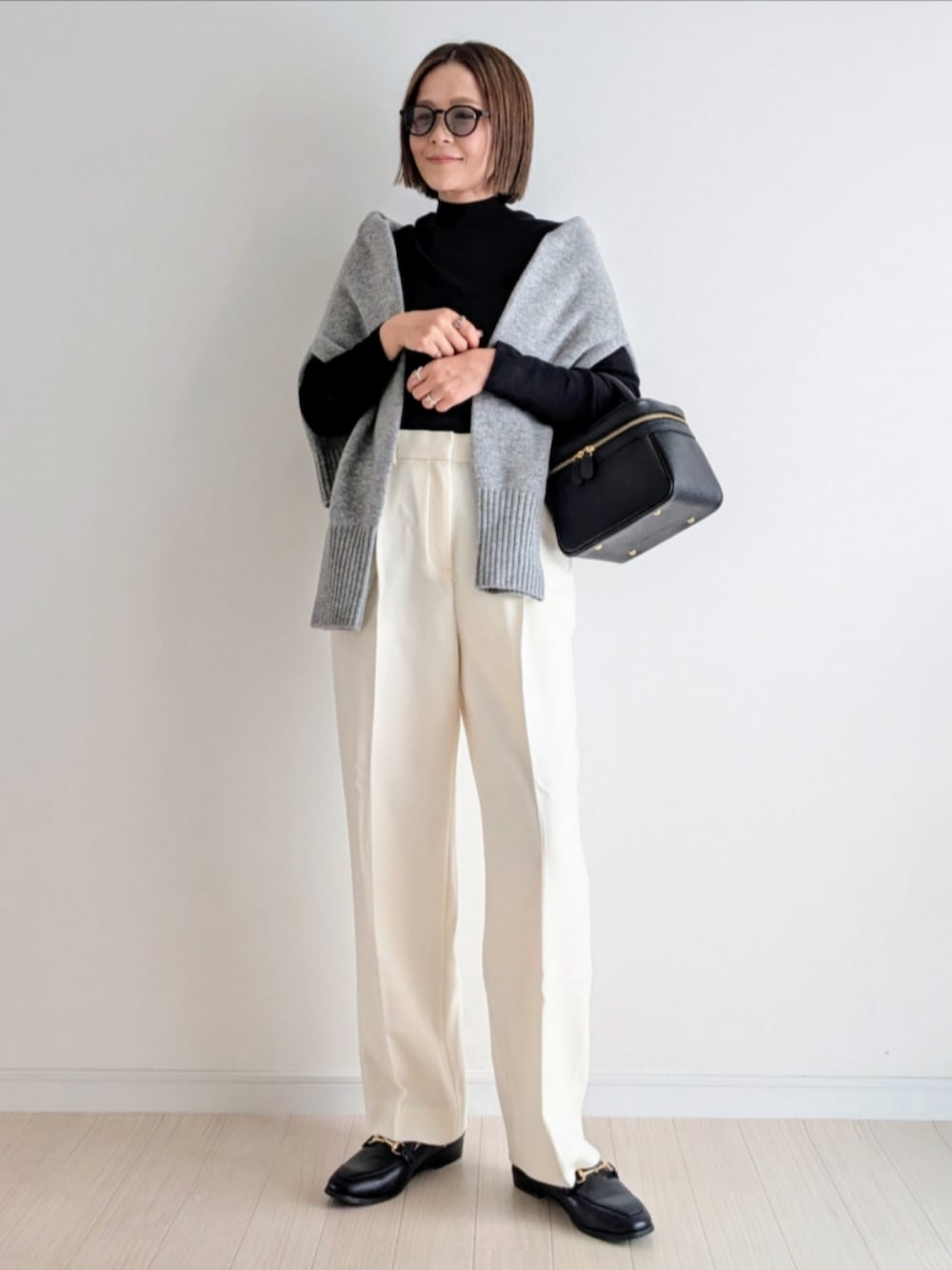 ブラック系のハンドバッグ、ブラック系のニット/セーター、グレー系のニット/セーターを着用したレディースの秋コーディネートの3枚目の写真