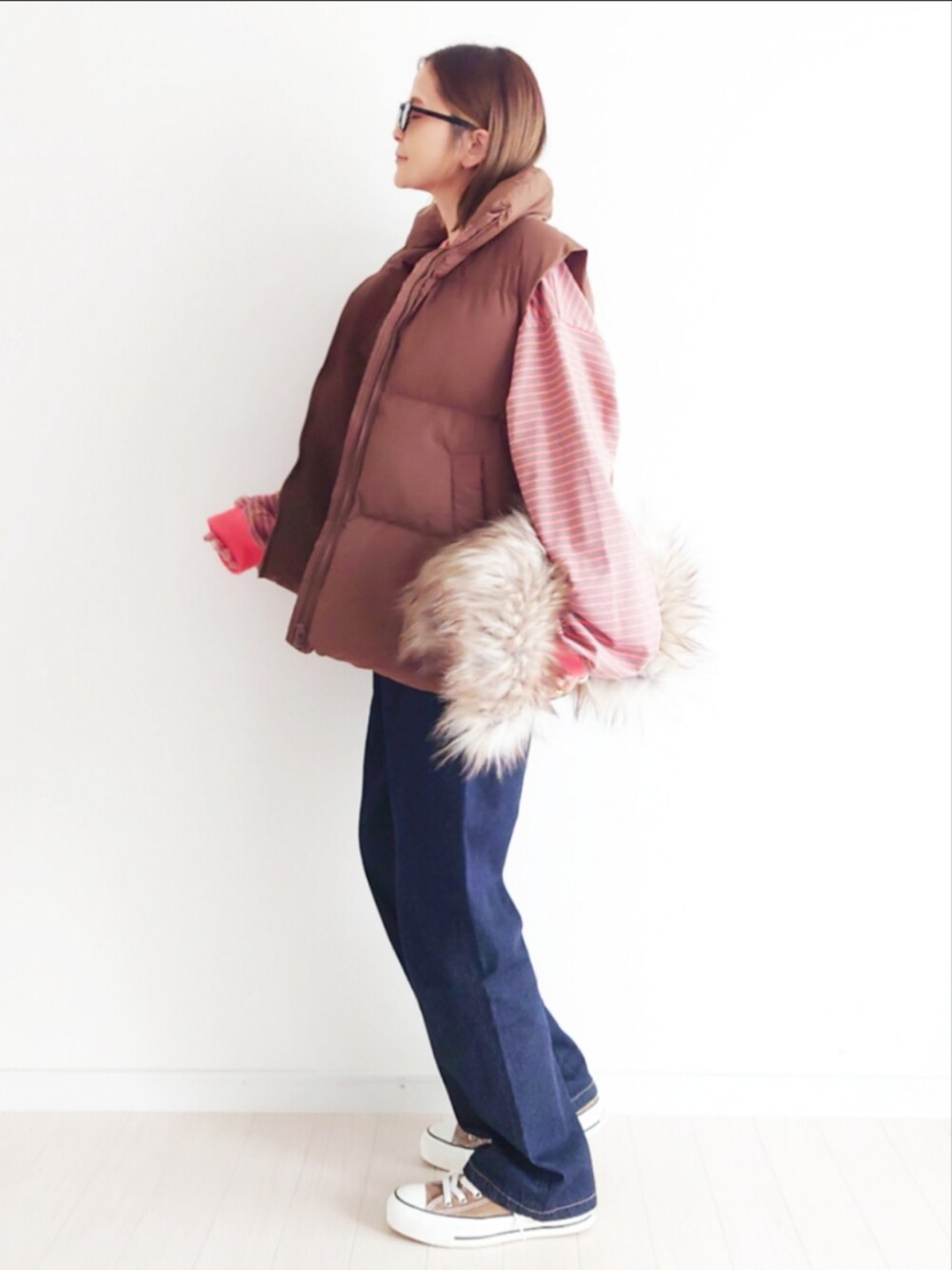 ブラウン系のTシャツ/カットソー、ブルー系のデニムパンツ、ブラウン系のダウンベストを着用したレディースの秋コーディネートの5枚目の写真