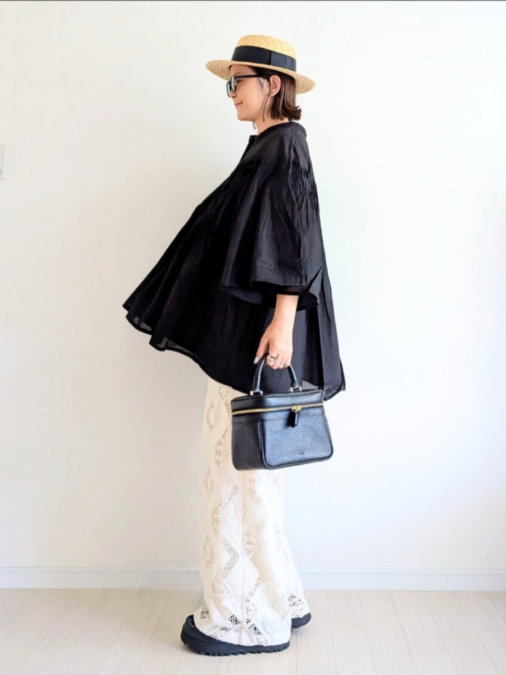 ブラック系のハンドバッグ、ブラック系のサンダル、ブラック系のシャツ/ブラウスを着用したレディースの夏コーディネートの3枚目の写真