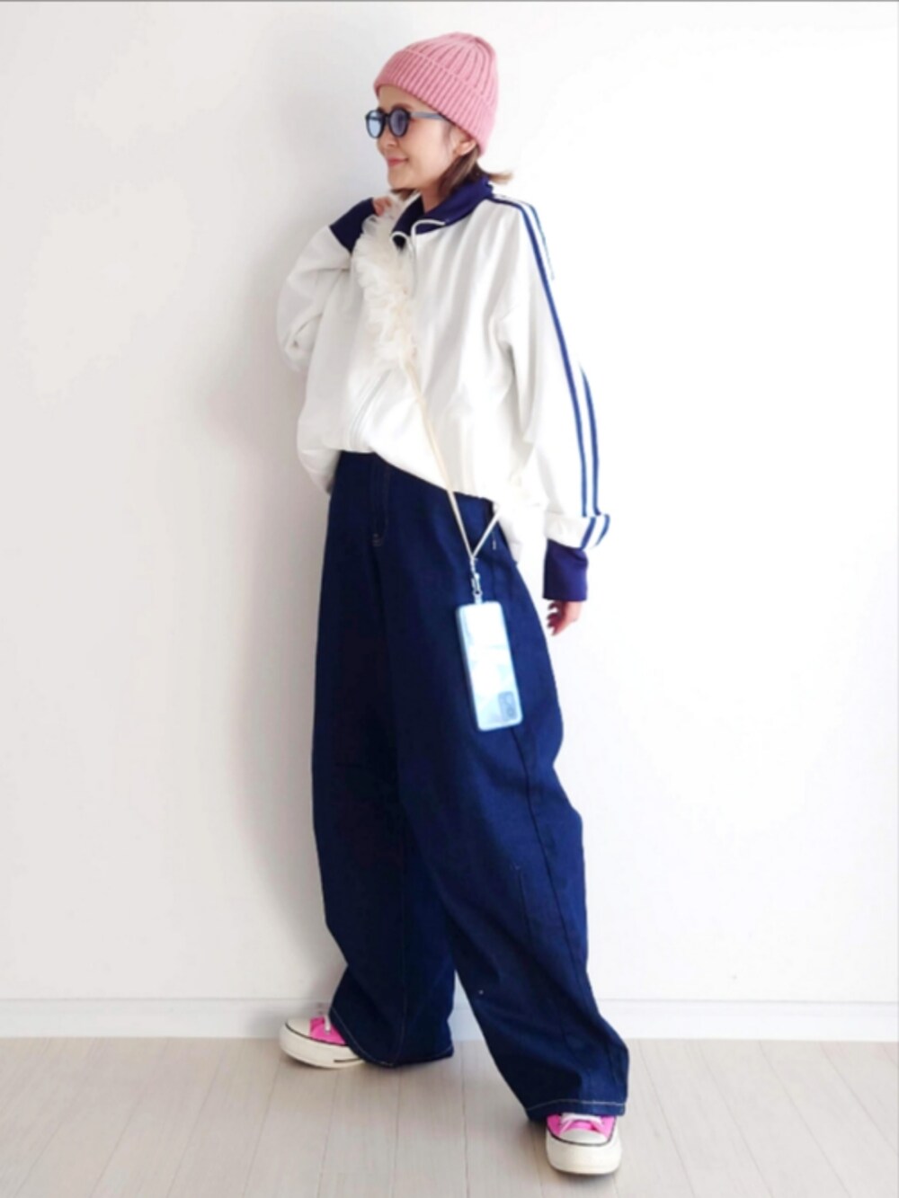 ホワイト系のジャージ、ブルー系のデニムパンツ、ピンク系のスニーカーを着用したレディースの冬コーディネートの3枚目の写真