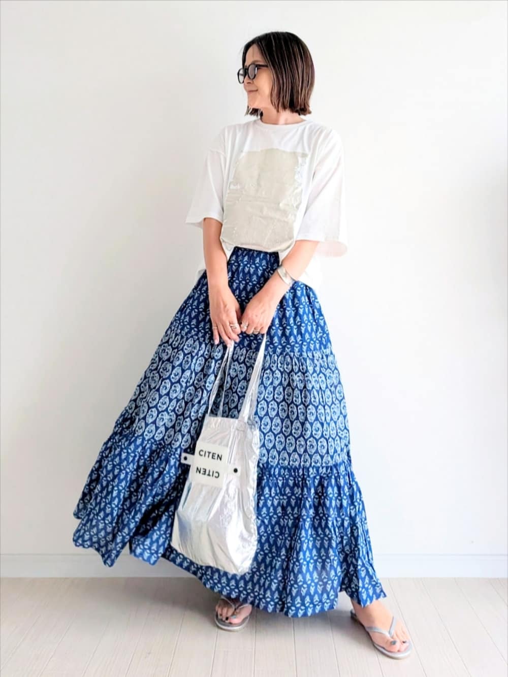 ブルー系のスカート、ホワイト系のTシャツ/カットソー、シルバー系のトートバッグを着用したレディースの夏コーディネートの2枚目の写真