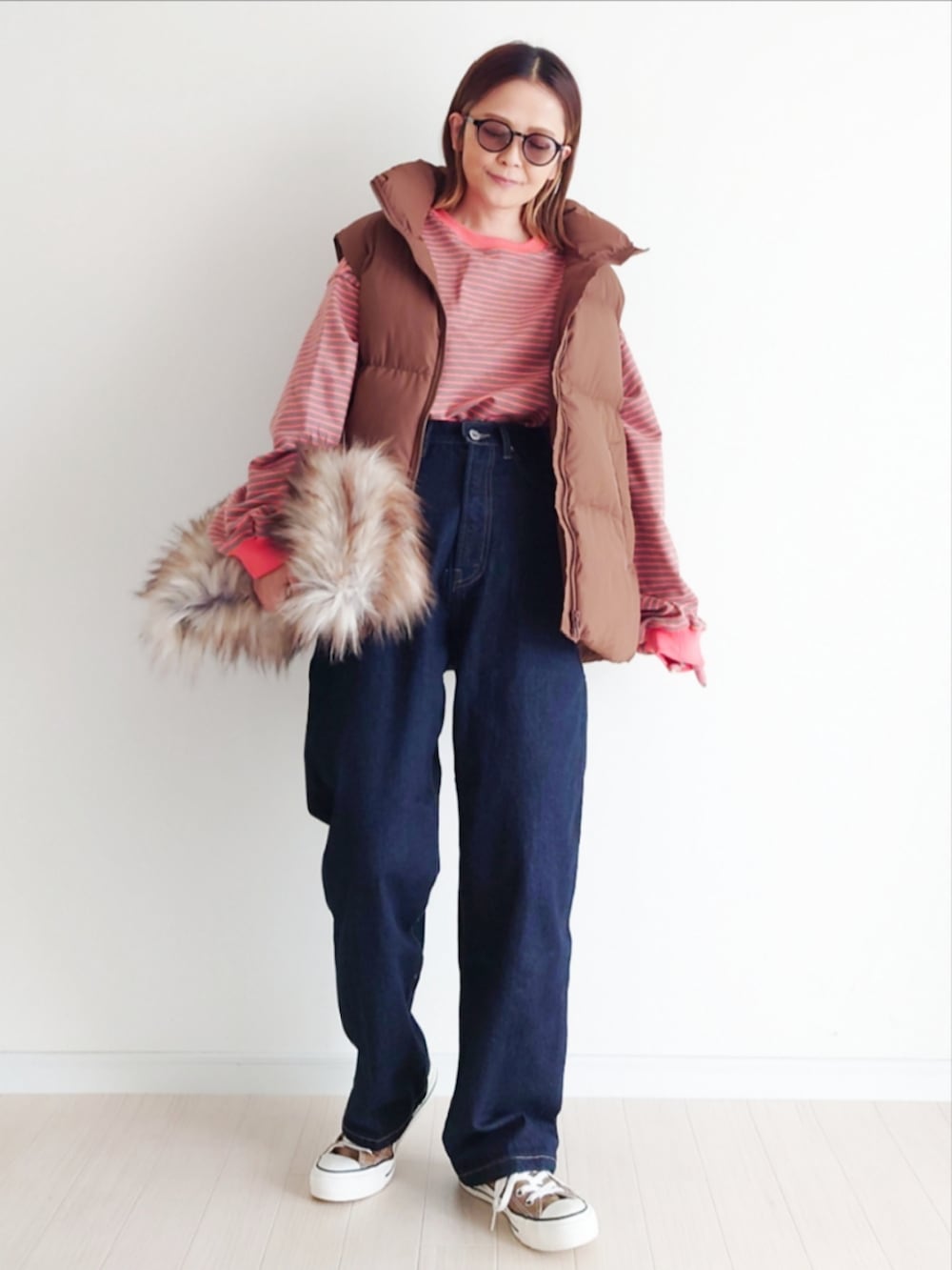 ブラウン系のTシャツ/カットソー、ブルー系のデニムパンツ、ブラウン系のダウンベストを着用したレディースの秋コーディネートの2枚目の写真