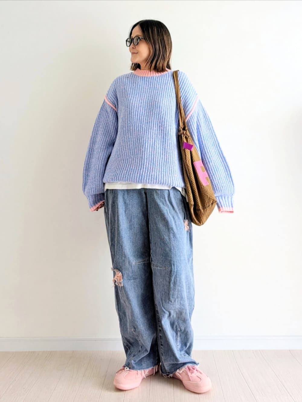 ピンク系のニット/セーター、ブルー系のデニムパンツ、ピンク系のスニーカーを着用したレディースの秋コーディネートの2枚目の写真
