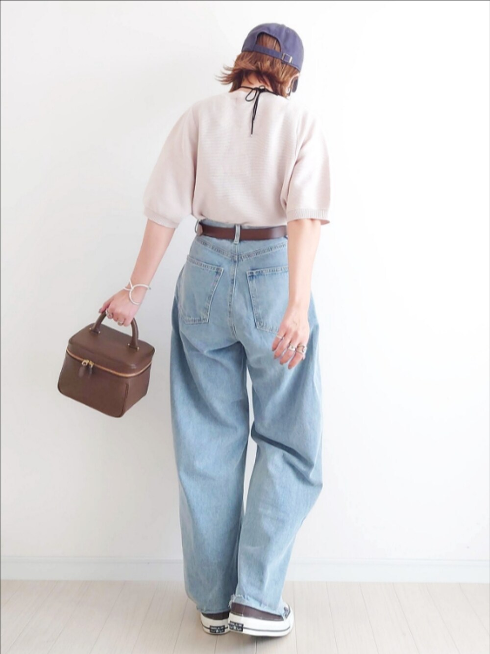 ホワイト系のニット/セーター、ブルー系のデニムパンツ、ブラウン系のハンドバッグを着用したレディースの秋コーディネートの4枚目の写真