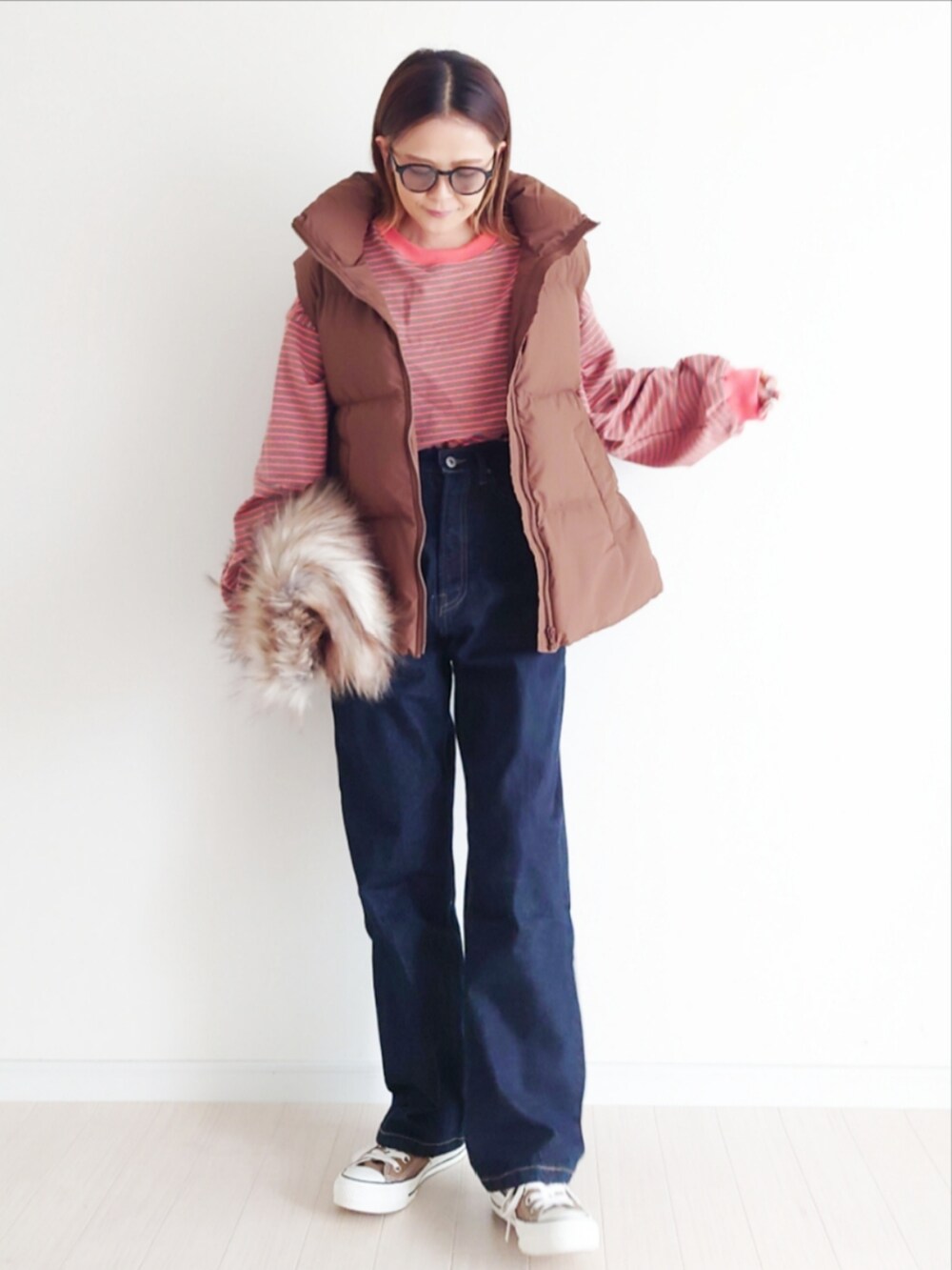 ブラウン系のTシャツ/カットソー、ブルー系のデニムパンツ、ブラウン系のダウンベストを着用したレディースの秋コーディネートの3枚目の写真