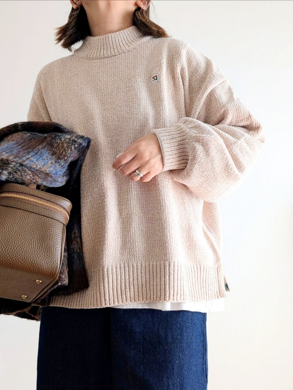 ブラウン系のテーラードジャケット、ベージュ系のニット/セーター、ブルー系のデニムパンツを着用したレディースの秋コーディネートの5枚目の写真