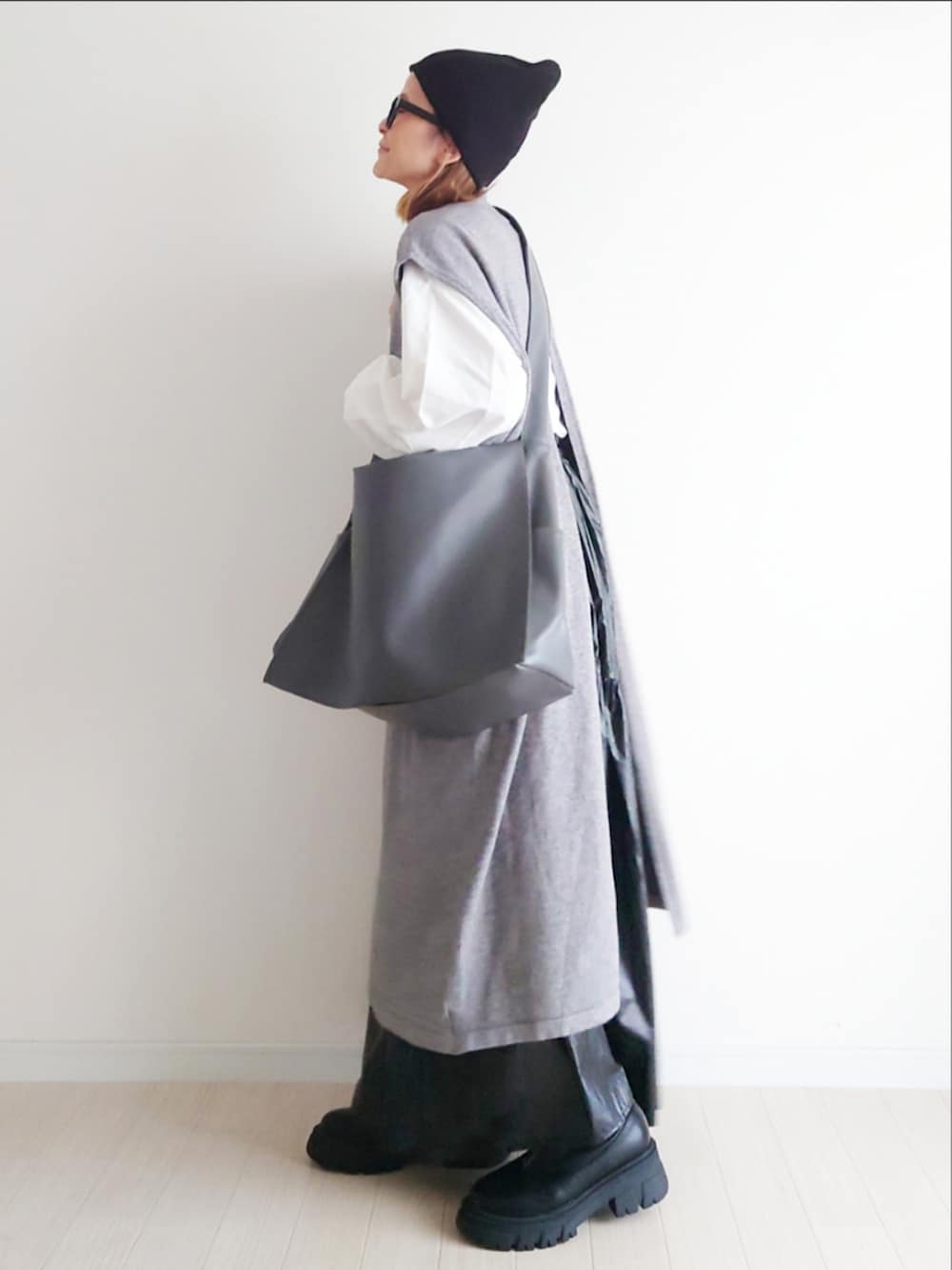 グレー系のワンピース、グレー系のショルダーバッグ、ブラック系のブーツを着用したレディースの秋コーディネートの4枚目の写真