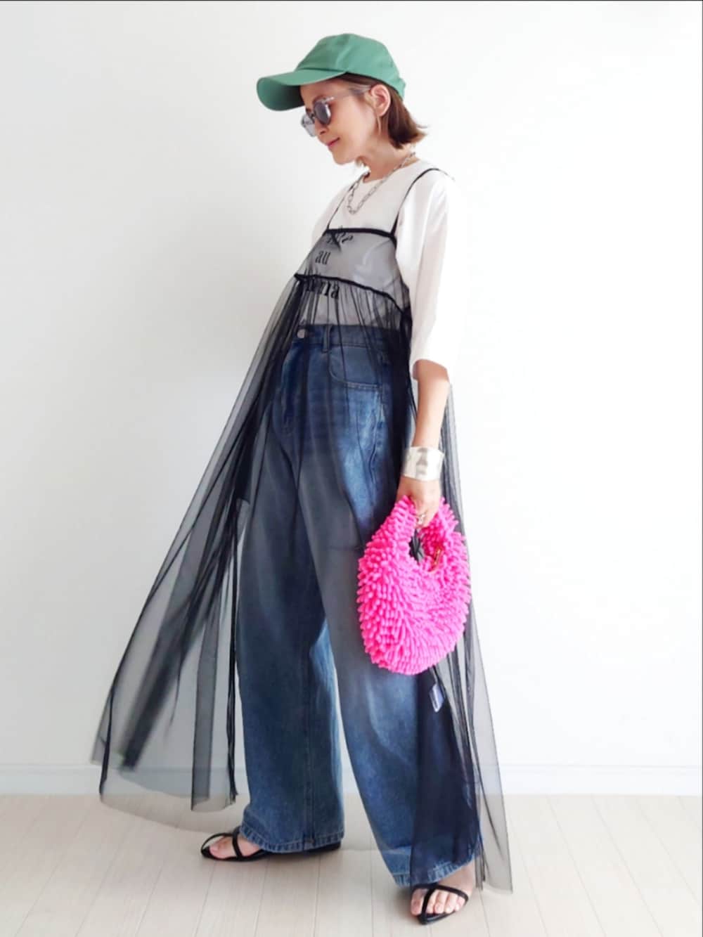 ブラック系のワンピース、ピンク系のトートバッグ、ブルー系のデニムパンツを着用したレディースの夏コーディネートの3枚目の写真