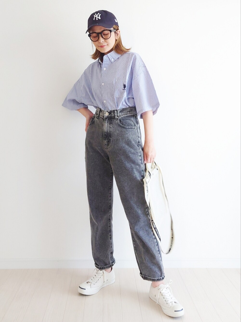 ブラック系のデニムパンツ、その他のショルダーバッグ、ホワイト系のスニーカーを着用したレディースの春コーディネートの2枚目の写真