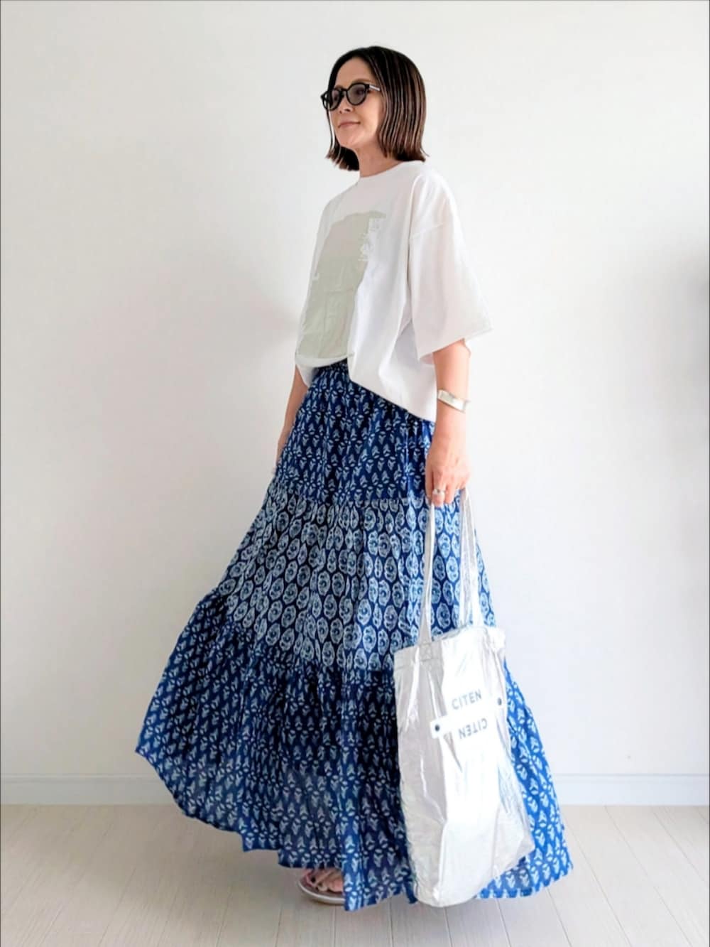 ブルー系のスカート、ホワイト系のTシャツ/カットソー、シルバー系のトートバッグを着用したレディースの夏コーディネートの3枚目の写真