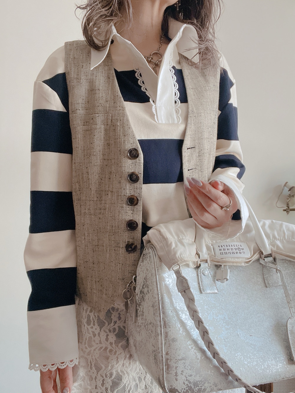 ホワイト系のトップス、グレー系のベスト、ホワイト系のワンピースを着用したレディースの春コーディネートの2枚目の写真