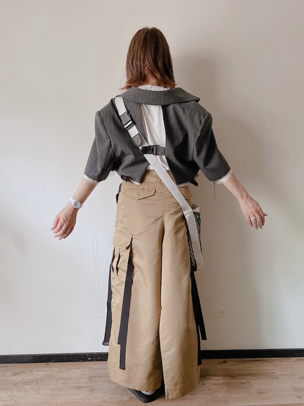 グレー系のテーラードジャケット、ホワイト系のショルダーバッグ、ブラック系のサンダルを着用したレディースの秋コーディネートの2枚目の写真