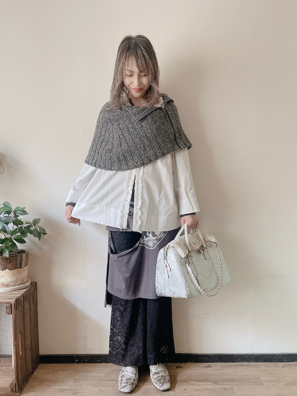 グレー系のニット/セーター、ホワイト系のシャツ/ブラウス、グレー系のスカートを着用したレディースの春コーディネートの3枚目の写真