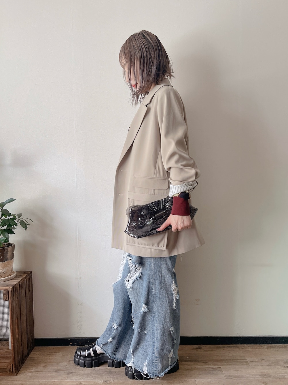 イエロー系のカーディガン/ボレロ、ベージュ系のテーラードジャケット、ブラック系のクラッチバッグを着用したレディースの春コーディネートの2枚目の写真