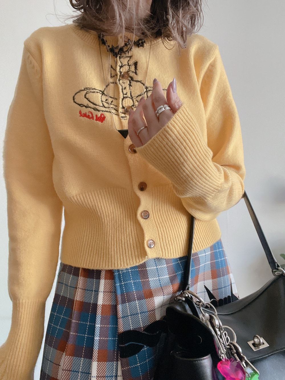 イエロー系のニット/セーター、ブラック系のダウンジャケット/コート、ブルー系のスカートを着用したレディースの冬コーディネートの2枚目の写真