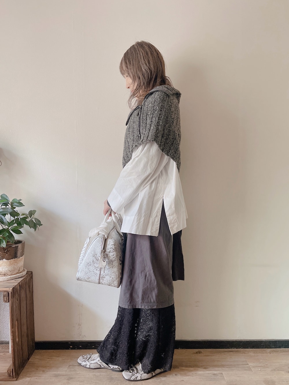 グレー系のニット/セーター、ホワイト系のシャツ/ブラウス、グレー系のスカートを着用したレディースの春コーディネートの2枚目の写真