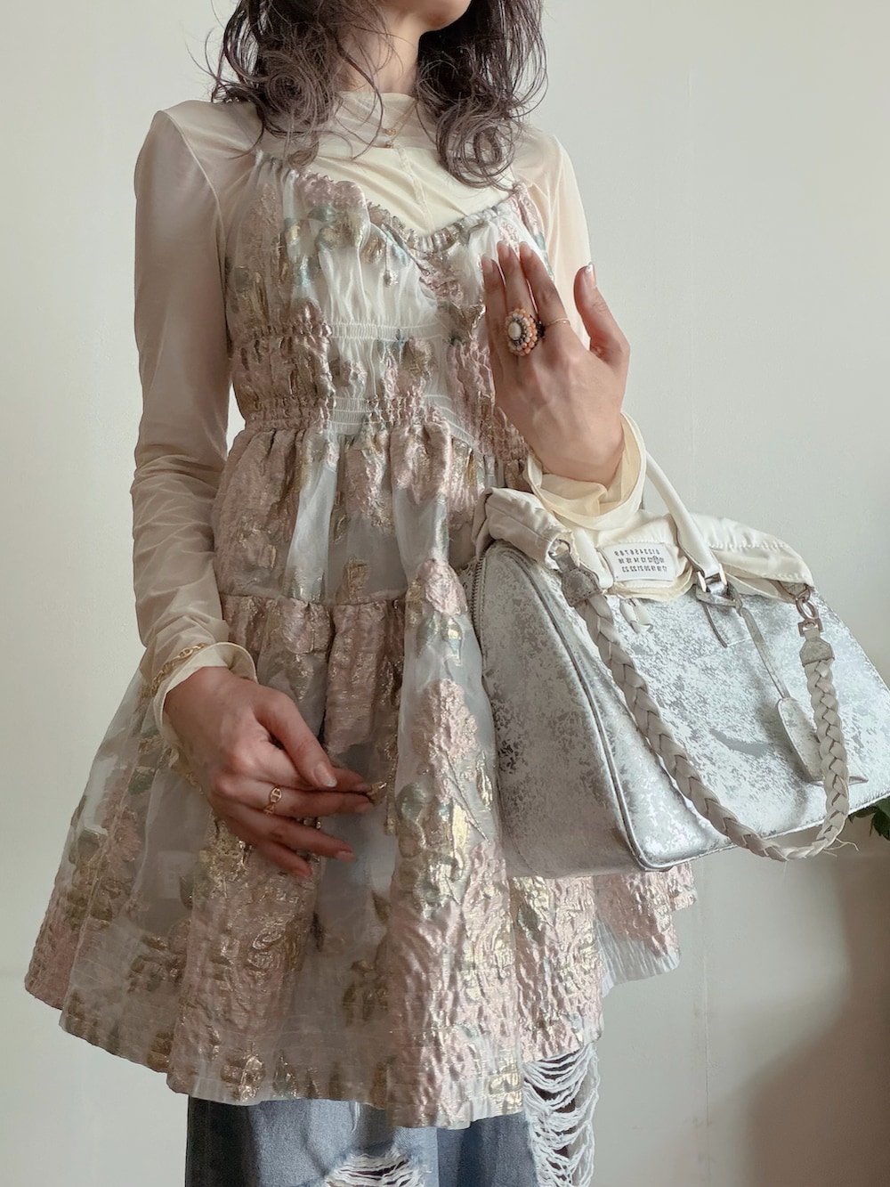 ピンク系のワンピース、ホワイト系のトップス、ブルー系のデニムパンツを着用したレディースの秋コーディネートの2枚目の写真