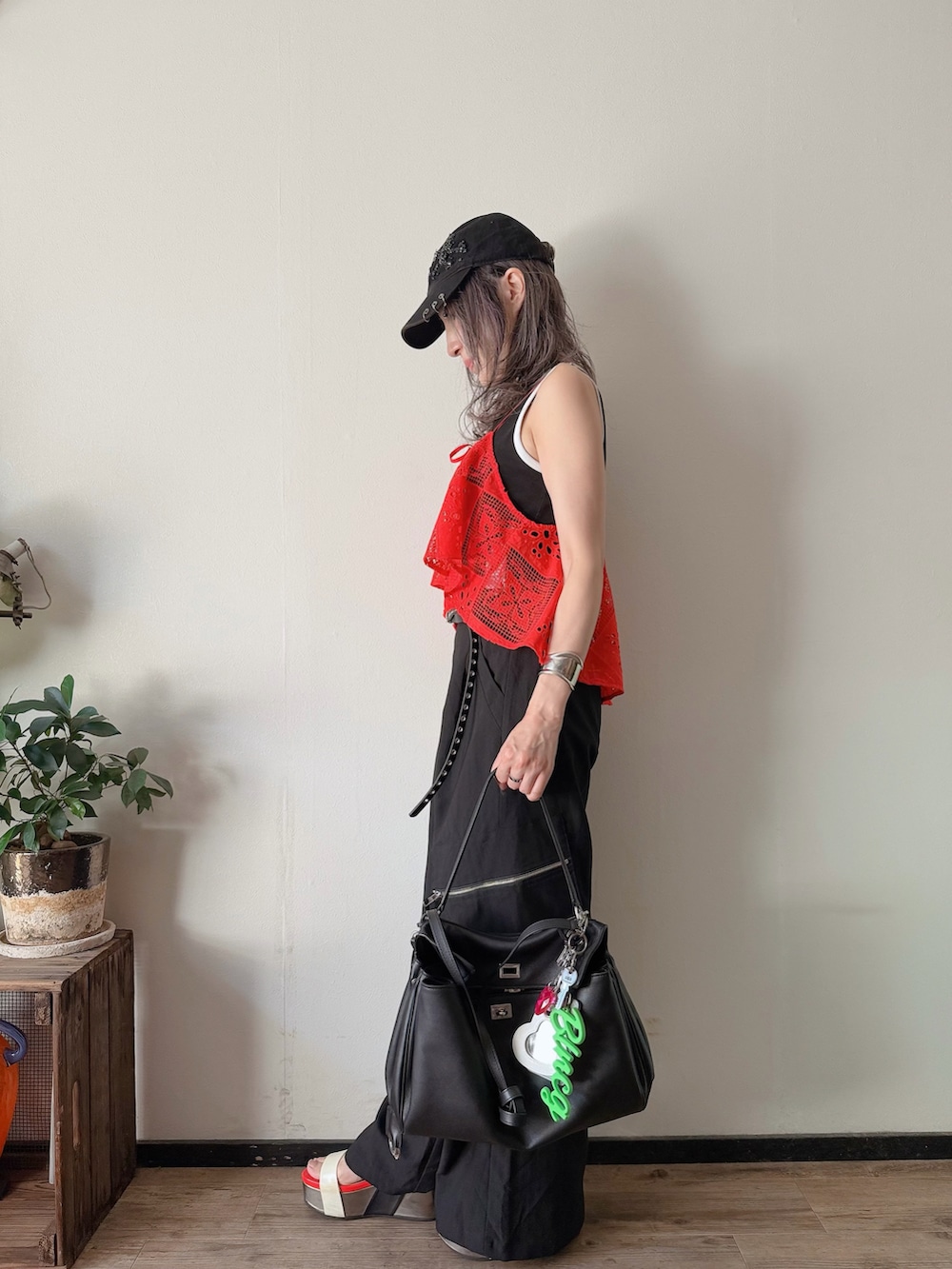 レッド系のキャミソール、ブラック系のカーゴパンツ、ブラック系のバッグを着用したレディースの夏コーディネートの3枚目の写真