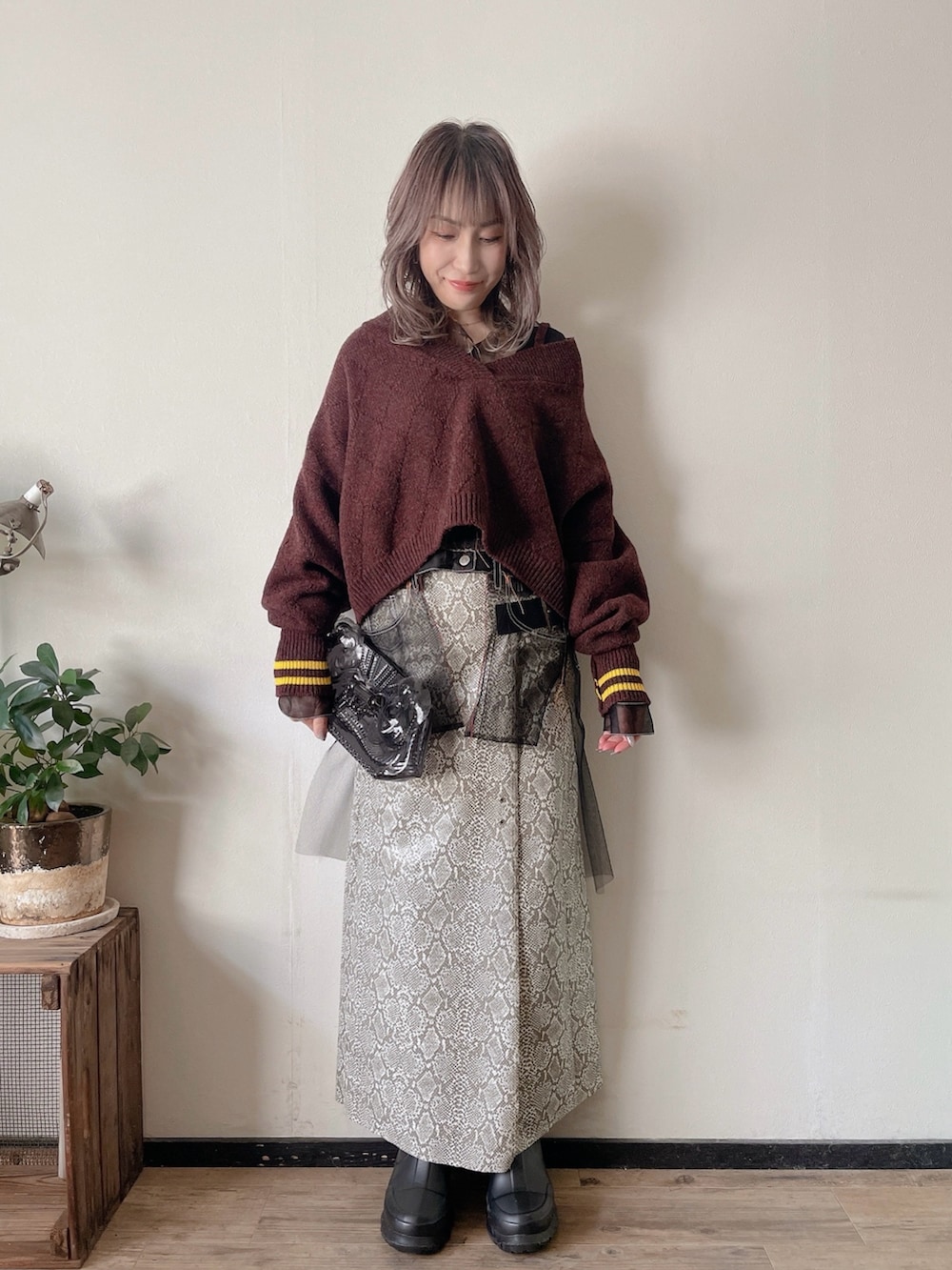 パープル系のニット/セーター、ブラック系のジャケット/アウター、ブラック系のクラッチバッグを着用したレディースの冬コーディネートの3枚目の写真