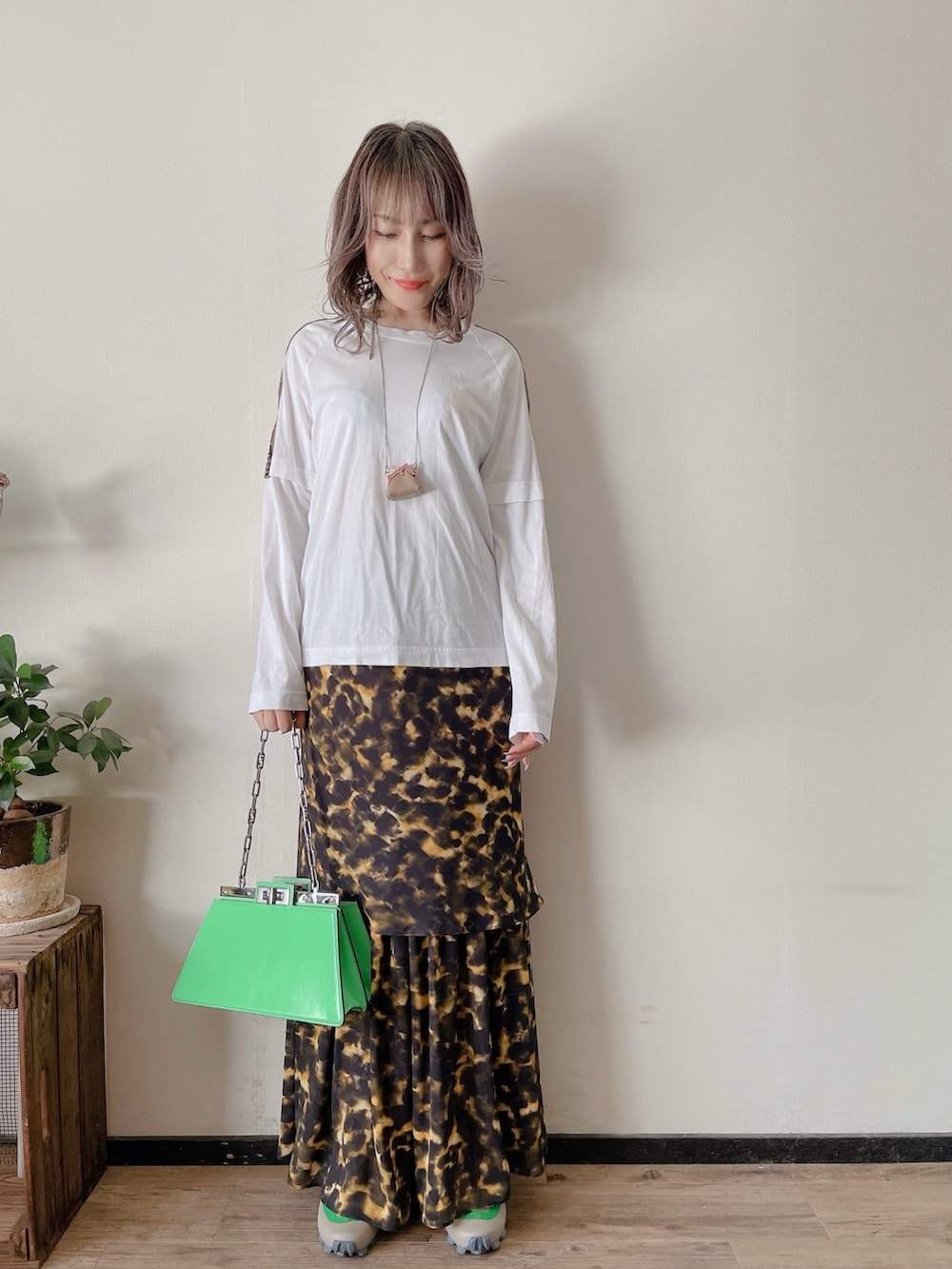 ホワイト系のTシャツ/カットソー、グリーン系のバッグ、ブラック系のスカートを着用したレディースの秋コーディネートの4枚目の写真