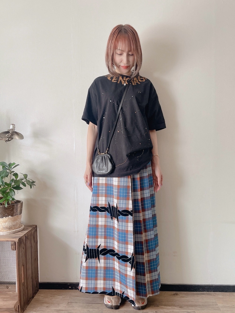 ブルー系のスカート、ブラック系のバッグ、ゴールド系のスニーカーを着用したレディースの秋コーディネートの2枚目の写真