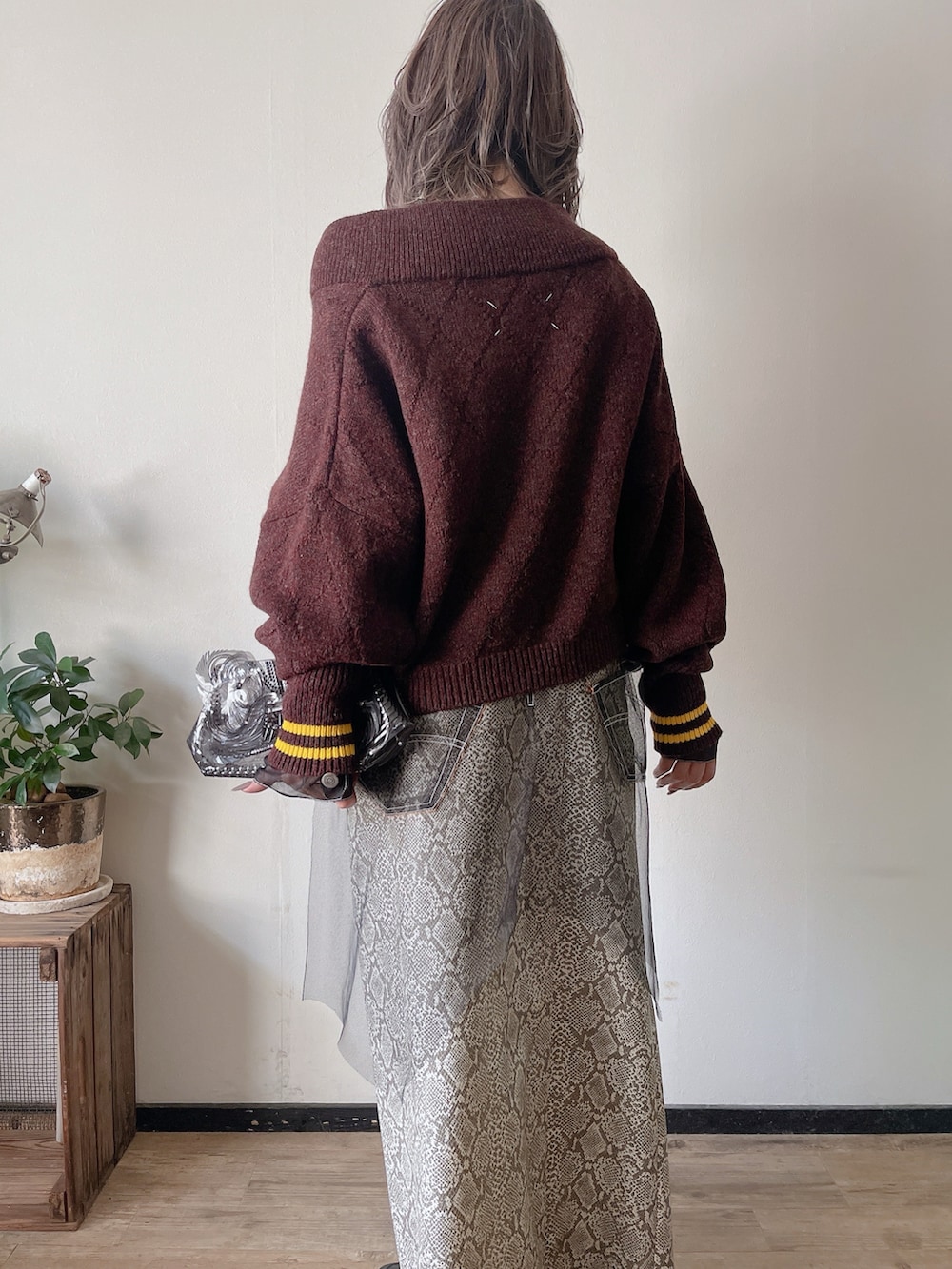 パープル系のニット/セーター、ブラック系のジャケット/アウター、ブラック系のクラッチバッグを着用したレディースの冬コーディネートの4枚目の写真