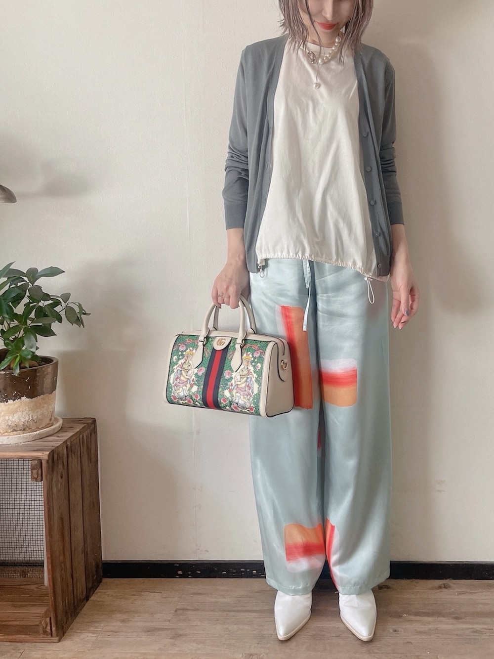 グリーン系のカーディガン/ボレロ、ブルー系のパンツ、シルバー系のネックレスを着用したレディースの春コーディネートの3枚目の写真