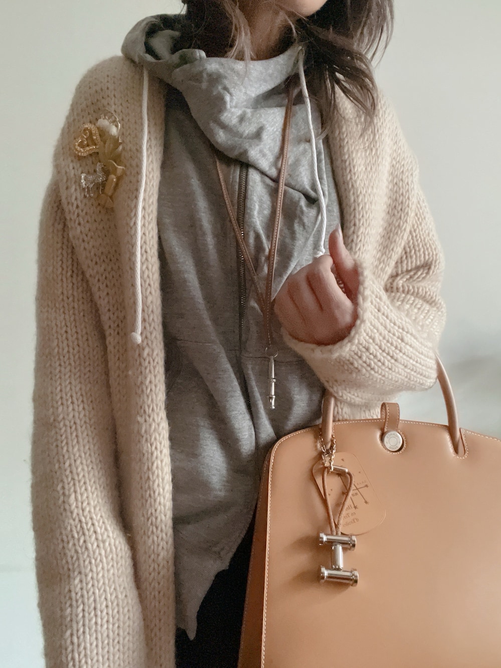 ブラック系のその他パンツ、ホワイト系のカーディガン/ボレロ、グレー系のパーカーを着用したレディースの冬コーディネートの2枚目の写真