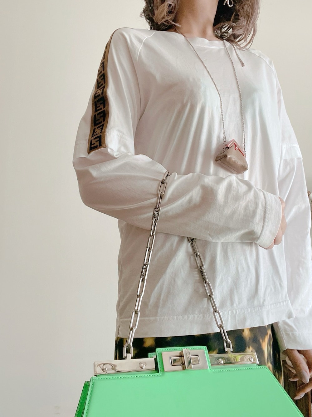 ホワイト系のTシャツ/カットソー、グリーン系のバッグ、ブラック系のスカートを着用したレディースの秋コーディネートの3枚目の写真