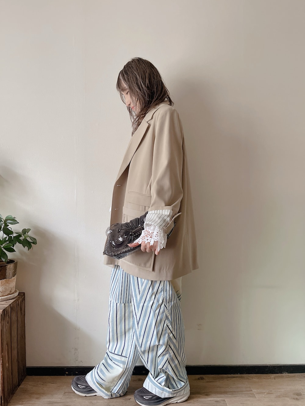 ベージュ系のテーラードジャケット、ブルー系のパンツ、ブラック系のクラッチバッグを着用したレディースの春コーディネートの2枚目の写真