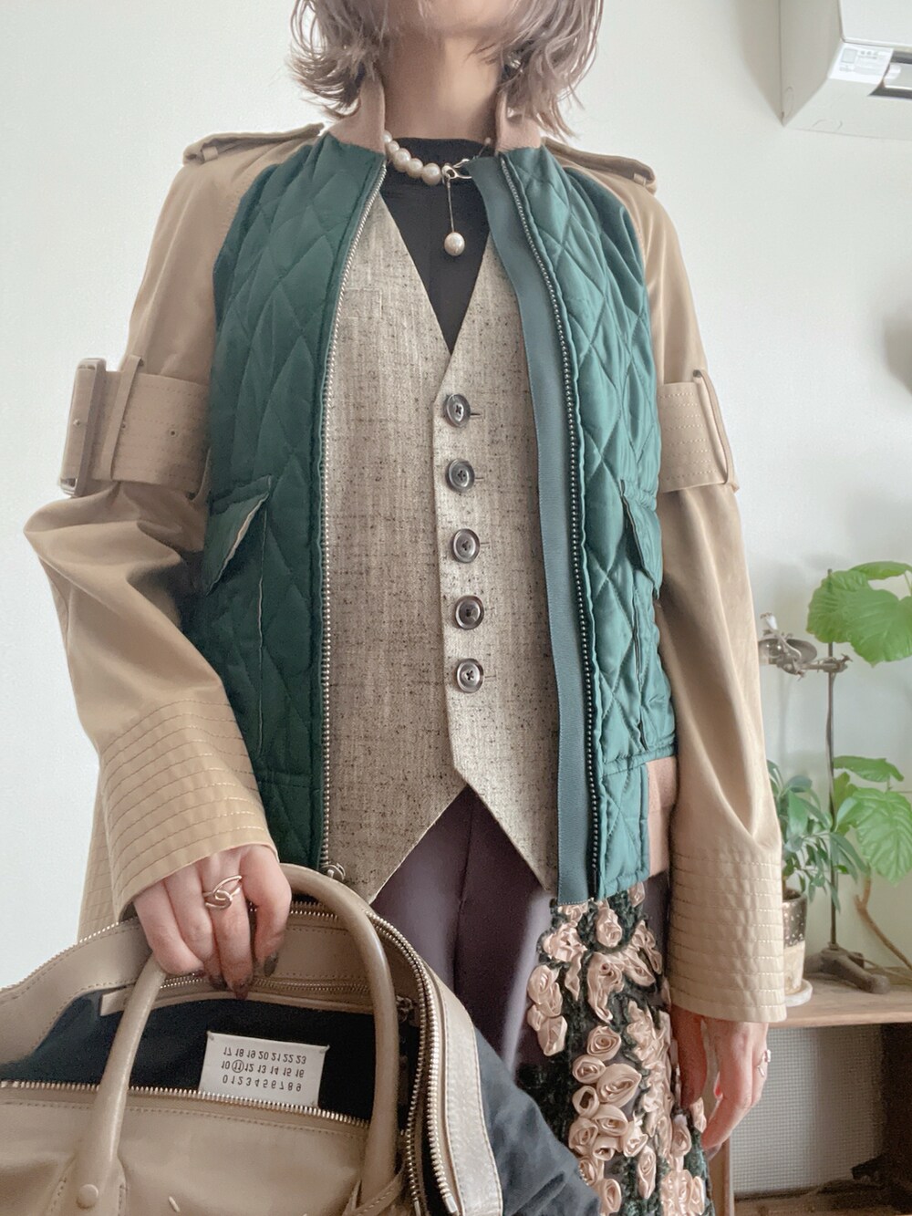 グレー系のベスト、ブラック系のトップス、グリーン系のジャケット/アウターを着用したレディースの春コーディネートの2枚目の写真