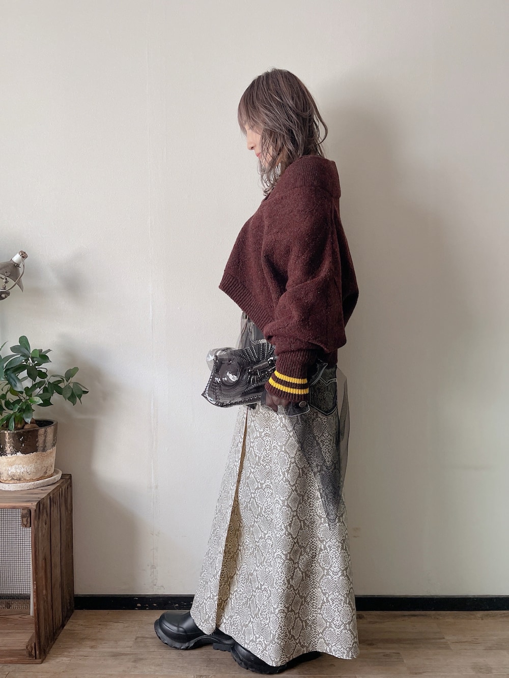 パープル系のニット/セーター、ブラック系のジャケット/アウター、ブラック系のクラッチバッグを着用したレディースの冬コーディネートの2枚目の写真