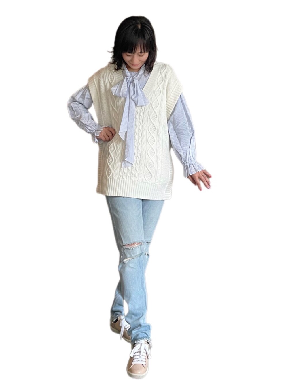 ブルー系のデニムパンツ、ピンク系のスニーカー、ホワイト系のベストを着用したレディースの春コーディネートの2枚目の写真