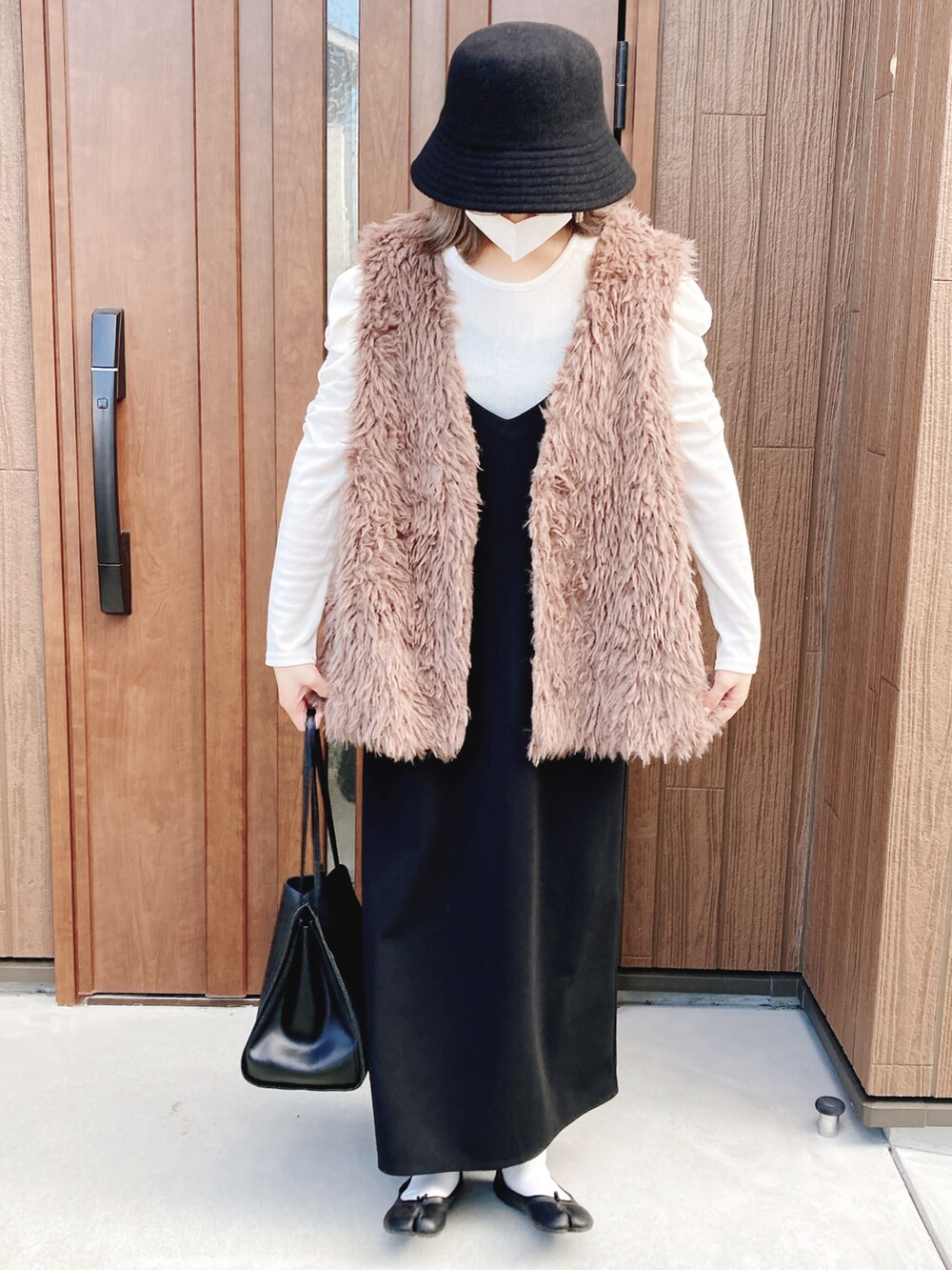 ブラック系のジャンパースカート、ホワイト系のTシャツ/カットソー、ブラック系のパンプスを着用したレディースの秋コーディネートの2枚目の写真