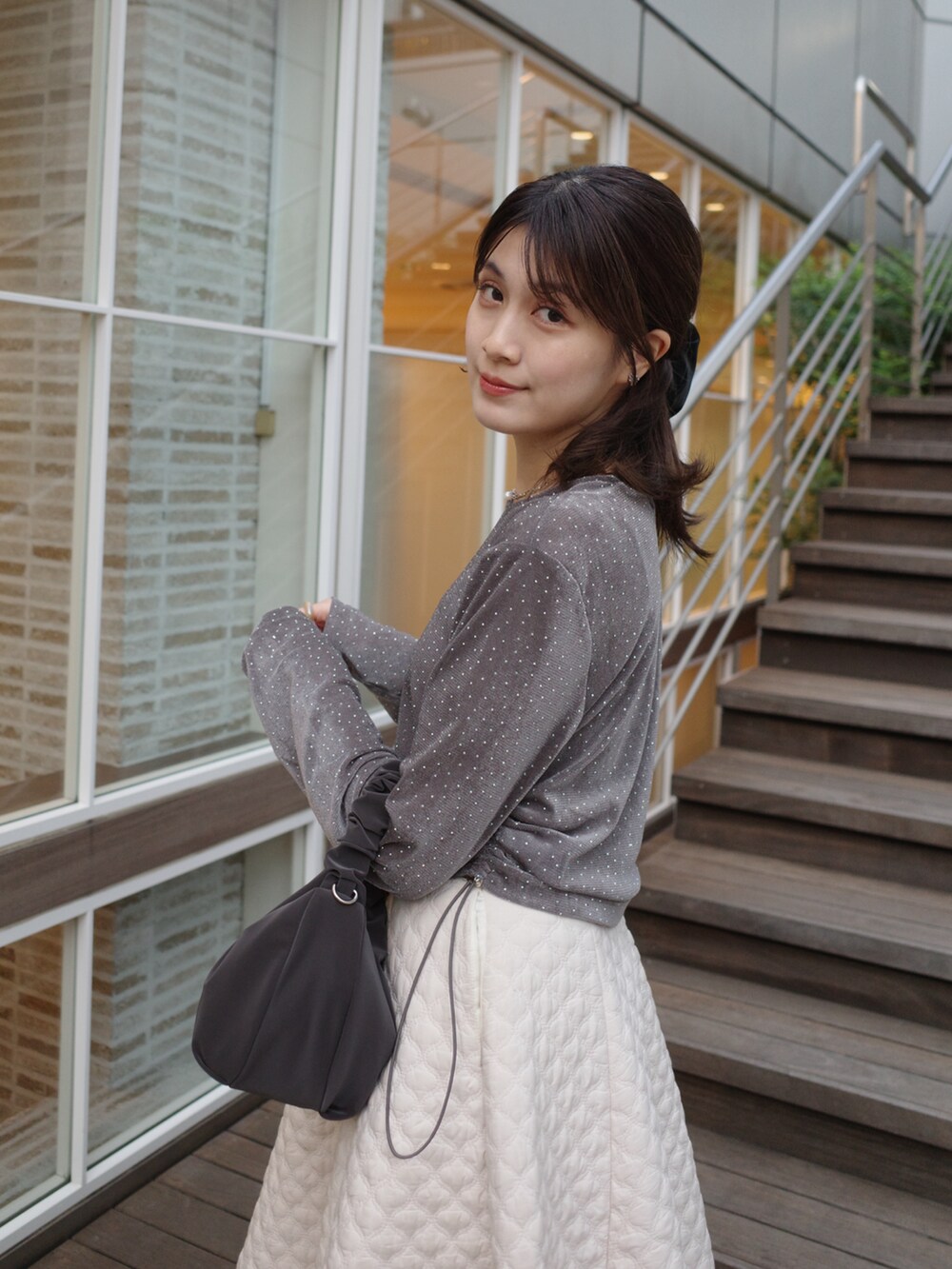 グレー系のTシャツ/カットソー、ホワイト系のスカート、ブラック系のバッグを着用したレディースの秋コーディネートの3枚目の写真