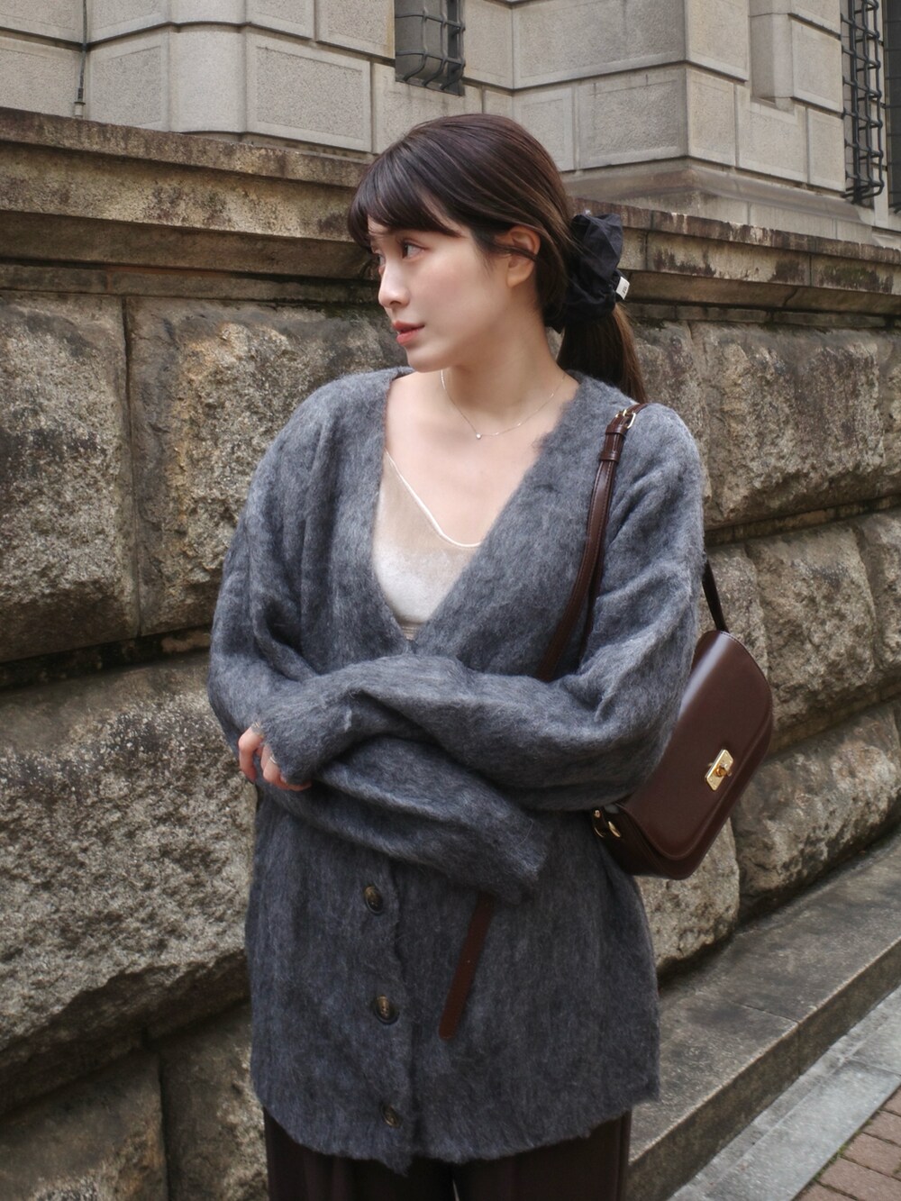 グレー系のカーディガン/ボレロ、ホワイト系のキャミソール、ブラウン系のパンツを着用したレディースの冬コーディネートの2枚目の写真