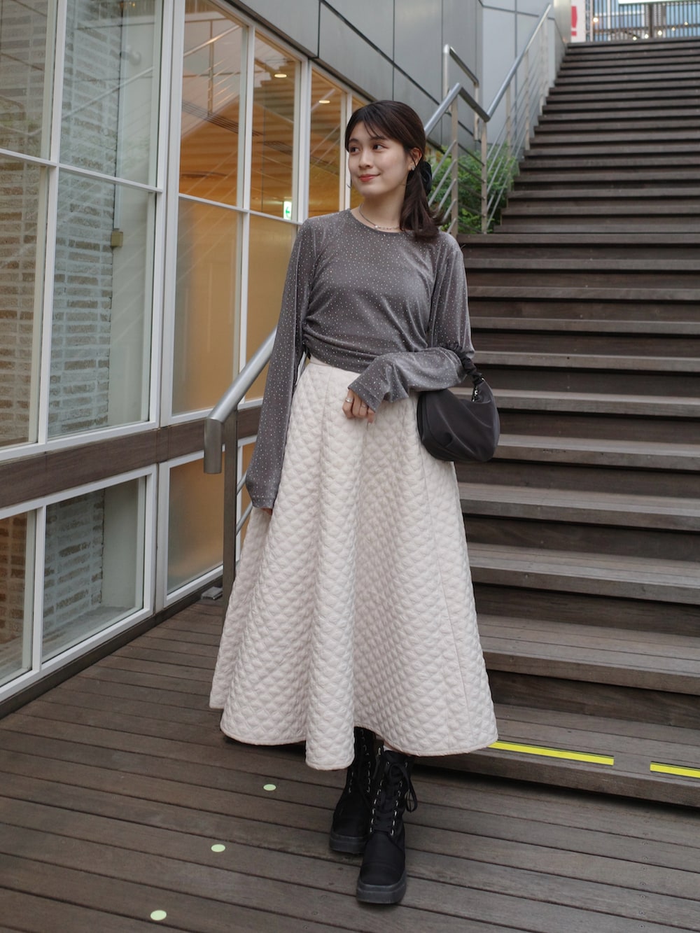 グレー系のTシャツ/カットソー、ホワイト系のスカート、ブラック系のバッグを着用したレディースの秋コーディネートの2枚目の写真