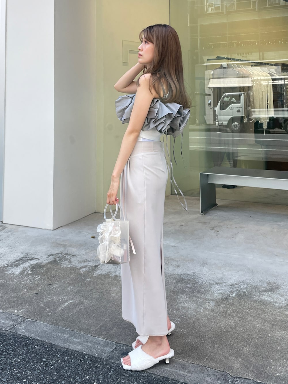 グレー系のベスト、ホワイト系のハンドバッグ、ベージュ系のスカートを着用したレディースの夏コーディネートの2枚目の写真