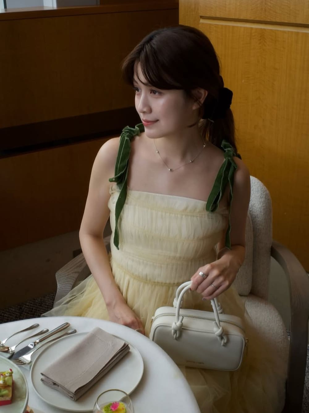 イエロー系のワンピース、ベージュ系のトートバッグ、ブラック系のシューズを着用したレディースの春コーディネートの2枚目の写真