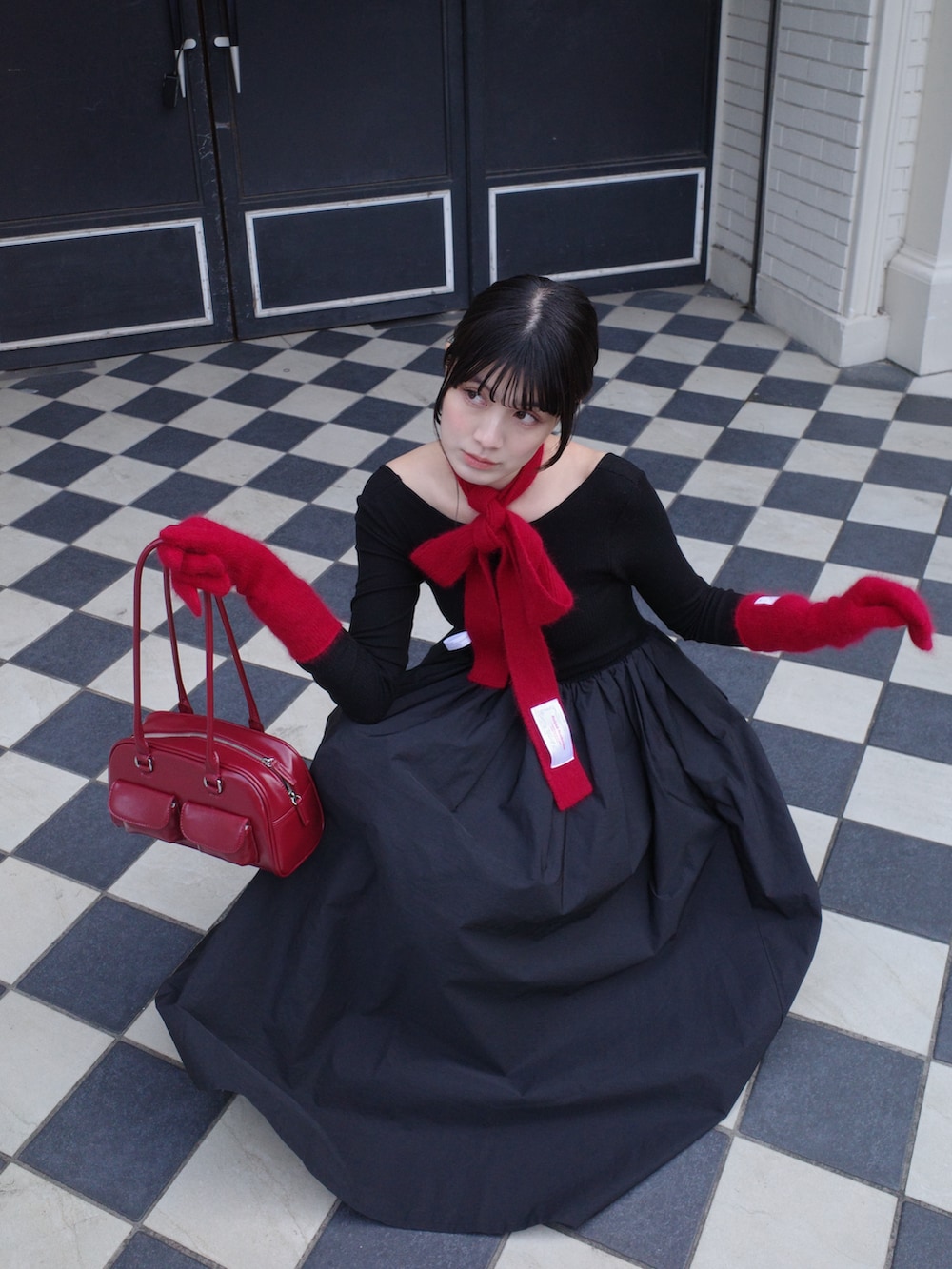 レッド系のバッグ、ブラック系のワンピース/ドレス、ピンク系の手袋を着用したレディースの冬コーディネートの2枚目の写真