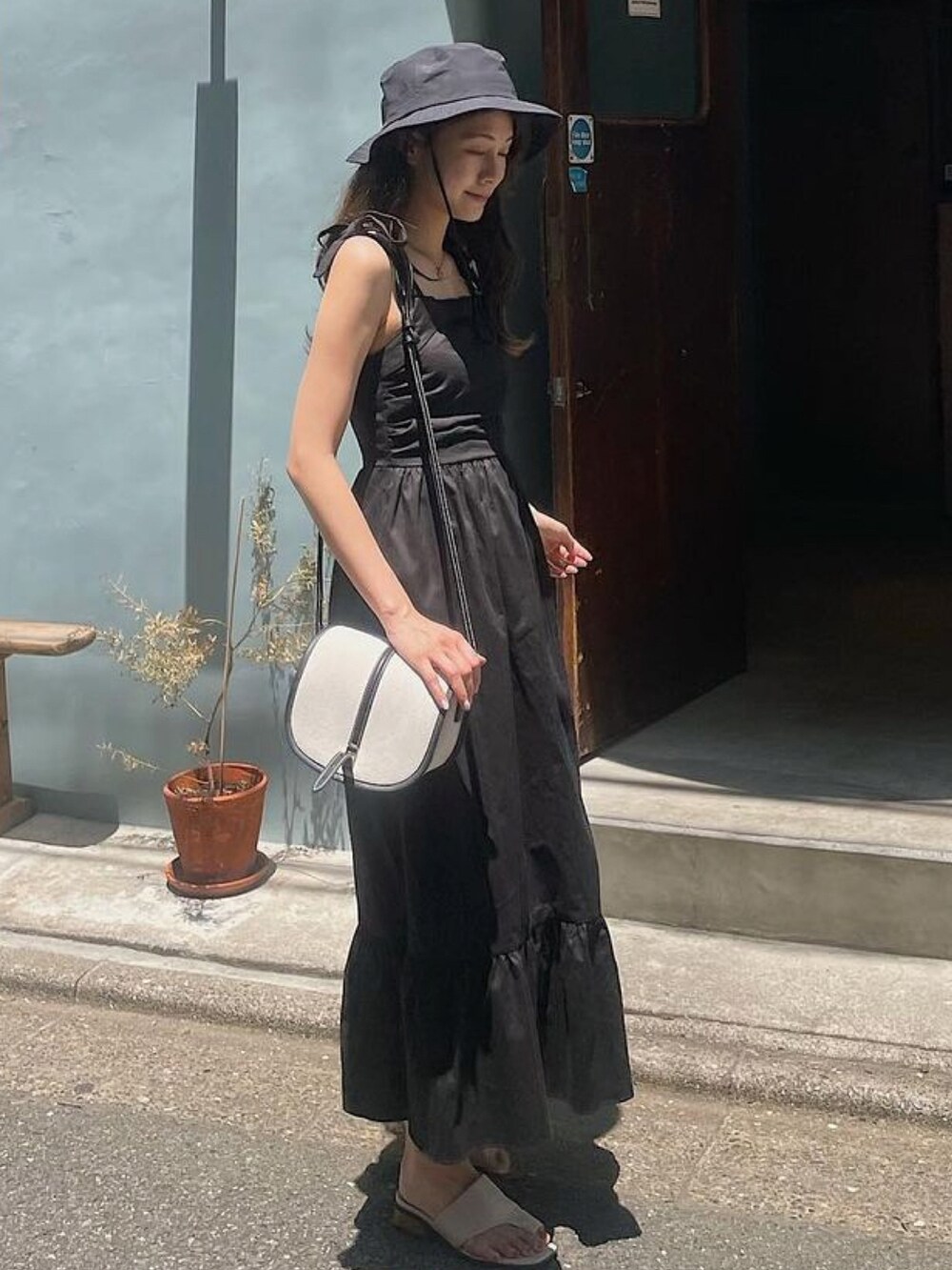 ブラック系のワンピース、ブラック系のハットを着用したレディースの夏コーディネートの2枚目の写真