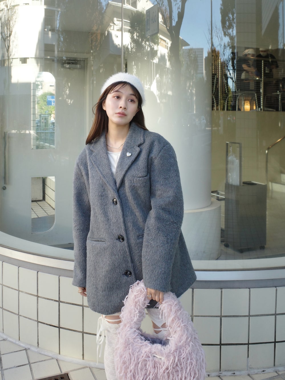 グレー系のテーラードジャケット、ピンク系のショルダーバッグ、ホワイト系のシューズを着用したレディースの秋コーディネートの2枚目の写真