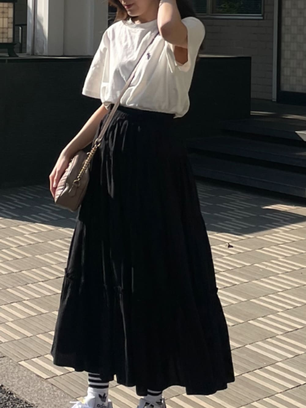 ブラック系のスカート、ホワイト系のTシャツ/カットソー、ホワイト系のスニーカーを着用したレディースの秋コーディネートの3枚目の写真