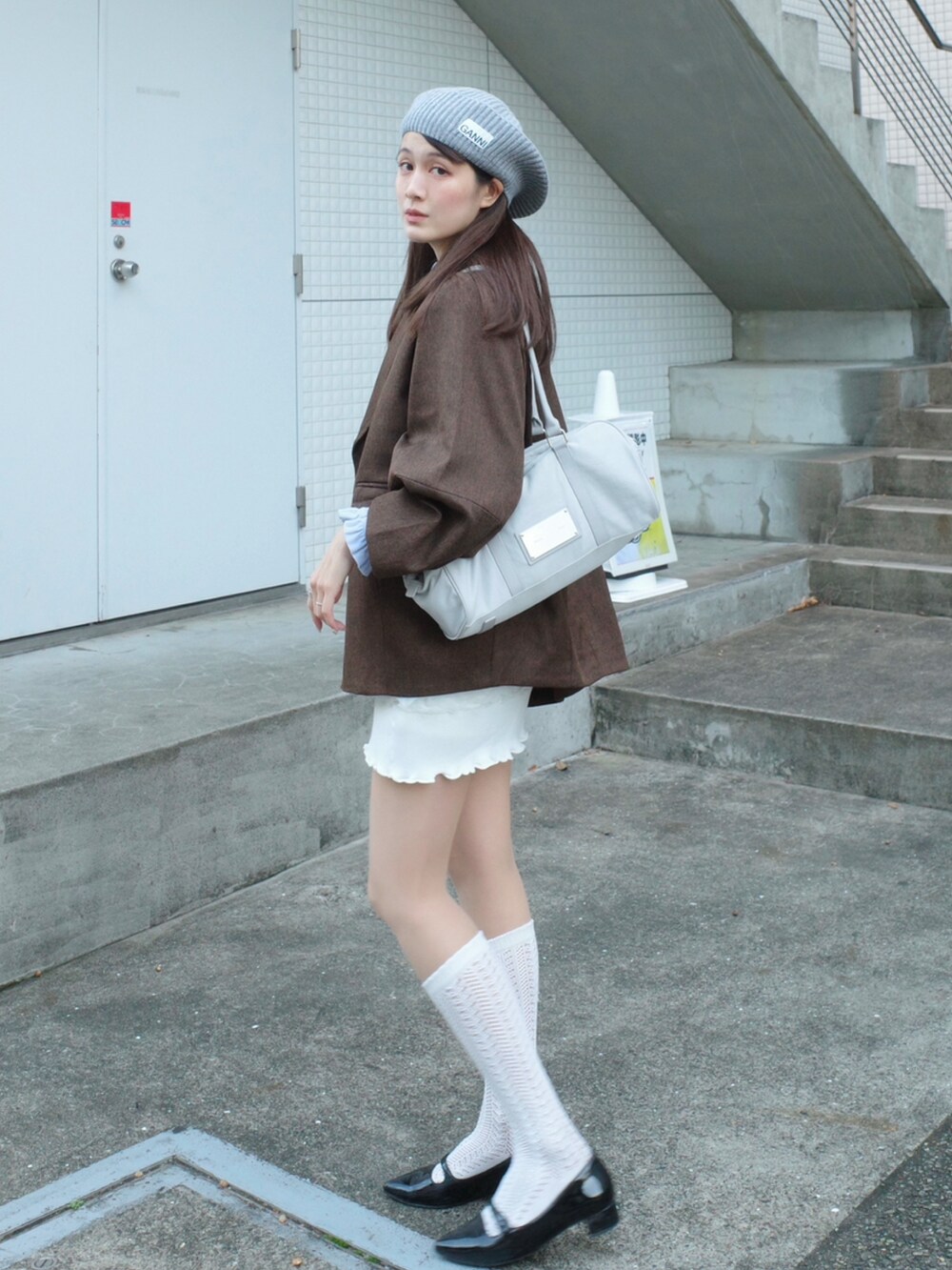 ブラウン系のテーラードジャケット、ホワイト系のスカート、グレー系のハンチング/ベレー帽を着用したレディースの冬コーディネートの2枚目の写真