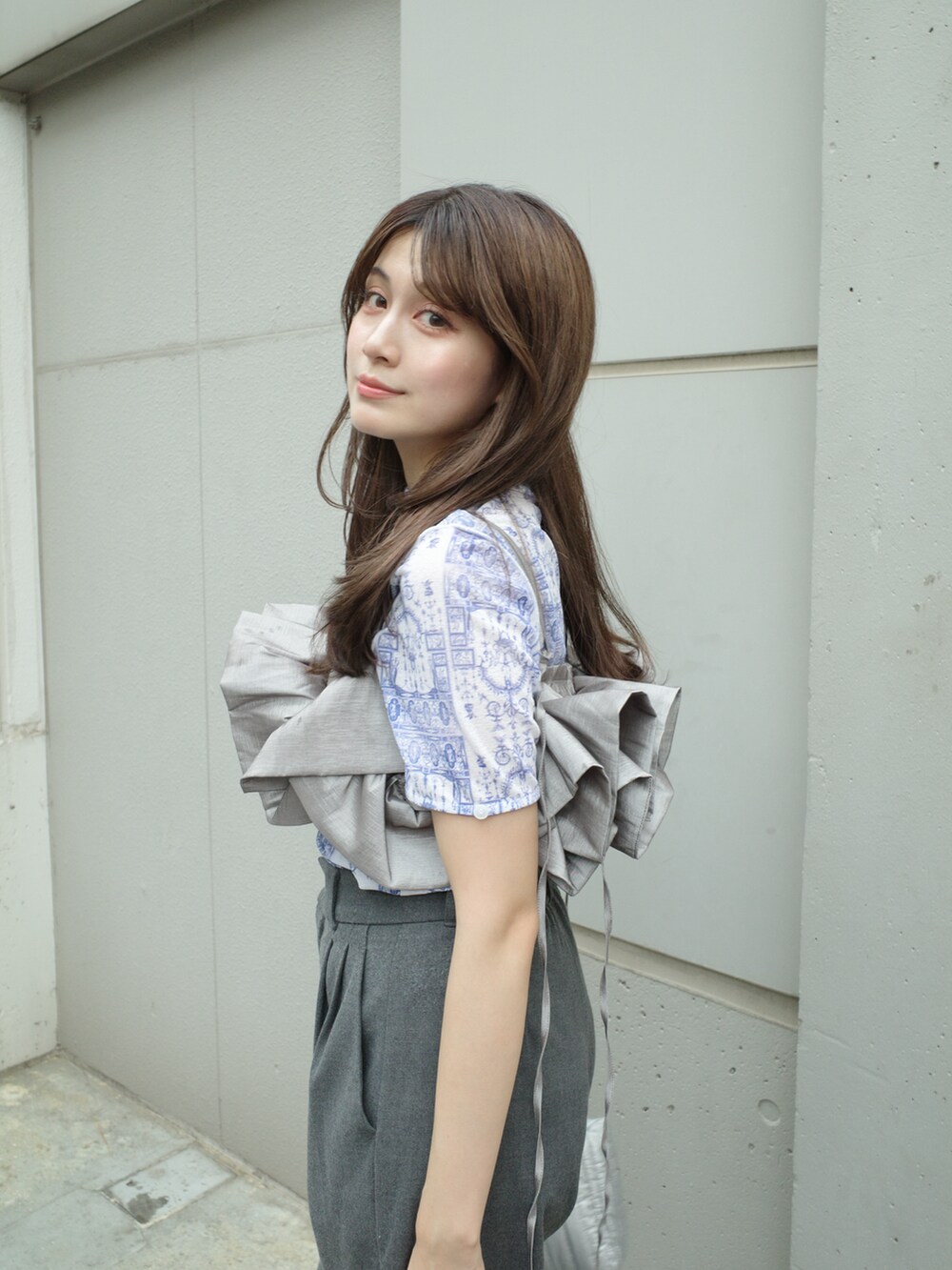 グレー系のベスト、ブルー系のTシャツ/カットソー、グレー系のパンツを着用したレディースの秋コーディネートの2枚目の写真